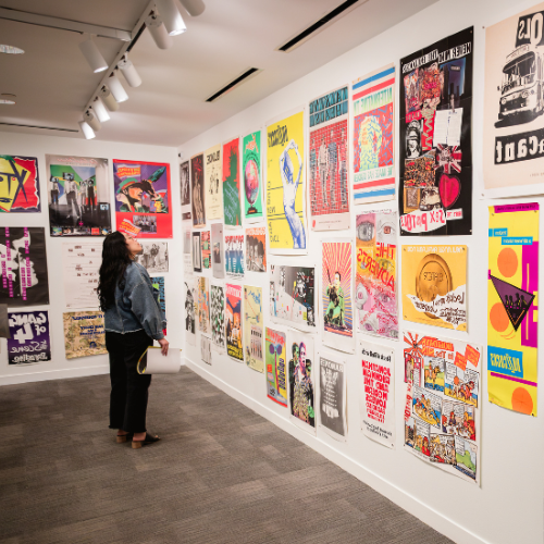 Woman looks at music posters on the wall of the Hawn Gallery during the Torn Apart exhibit